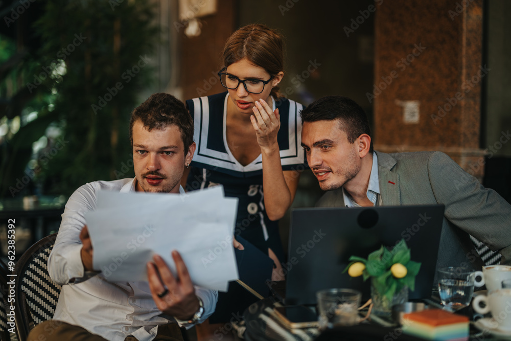 Obraz premium Business professionals collaborating in a modern office setting, reviewing documents and strategizing. The team is focused on teamwork and decision-making during a business meeting.