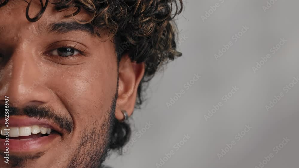 A mesmerizing portrait of an attractive confident Indian man with a toothy smile looking at the camera and smiling. Half-face portrait, blurred shot, close up. A mesmerizing portrait of an attractive confident Indian man with a toothy smile looking at the camera and smiling. Half-face portrait, blurred shot, close up.