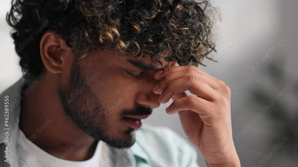Close up portrait of tired upset sad Indian man rubbing bridge of nose. Millennial Indian student touching face, wants to sleep, feels tension, headache, eye fatigue, needs rest.