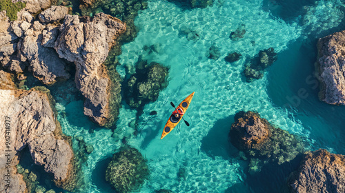Aerial view of a kayaker navigating through clear turquoise waters between rocky formations. This adventurous image is perfect for promoting outdoor activities, water sports, and the beauty of nature