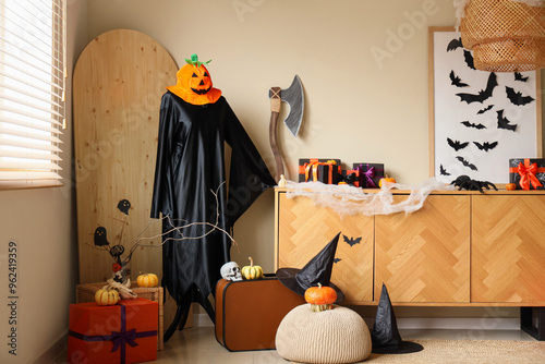 Interior of festive living room with wooden cabinet, Halloween decorations and gift boxes photo