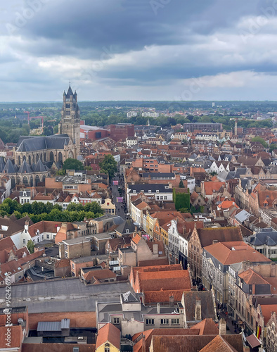 Brugge, Flanders, Belgium - June 22, 2024: Sint-Salvatorskathedraal, cathedral, in cityscape, urban jungle, seen from Halletoren under dense gray cloudscape photo