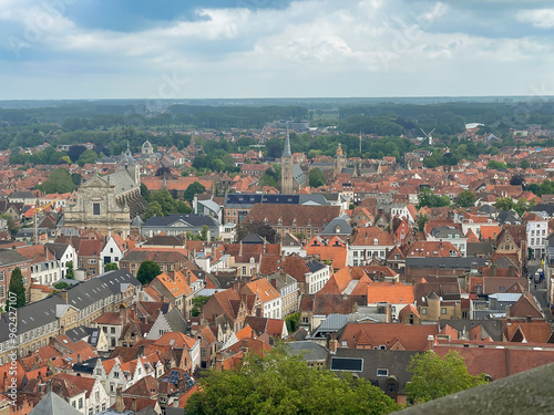 Brugge, Flanders, Belgium - June 22, 2024: From Halletoren: 4 churches, St. Walburge, St, Anna, English Convent, Jeruzalem church. Historic windmills along circle canal photo