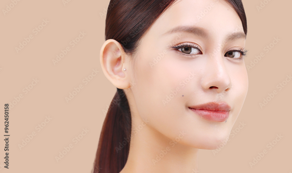 Fototapeta premium Close up face of beautiful young Asian woman with K beauty style makeup and perfect skin on isolated beige brown background. Facial and skin care concept for commercial advertising.