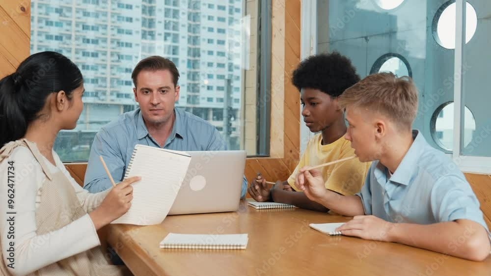 Smart girl ask teacher a question while show idea while diverse student working classwork. Group of multicultural children pointing at notebook while happy boy sharing idea at classroom. Edification