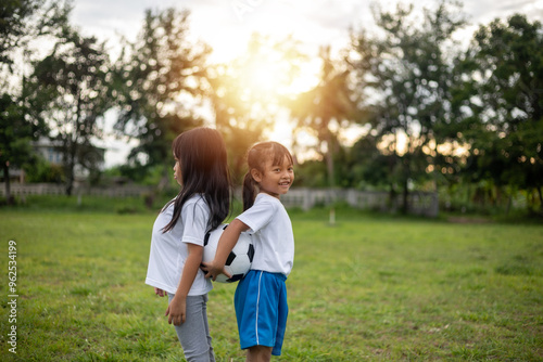 Two young girls are standing in a grassy field