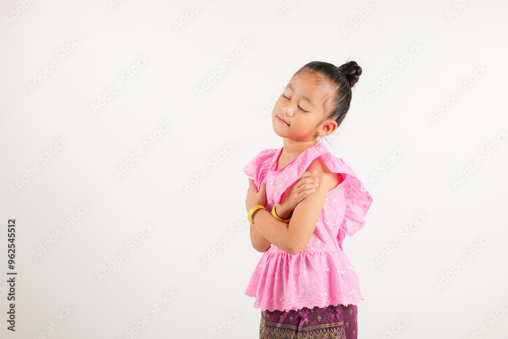 Portrait Thailand kid girl smiling traditional Thai dress costume hugging herself remember moment, studio isolated white background, kindergarten child love yourself carefree self care and self esteem Portrait Thailand kid girl smiling traditional Thai dress costume hugging herself remember moment, studio isolated white background, kindergarten child love yourself carefree self care and self esteem