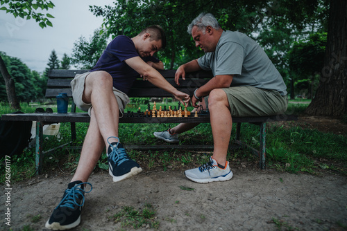 Two men engage in a focused chess game on a park bench surrounded by lush greenery, highlighting strategy and friendship.