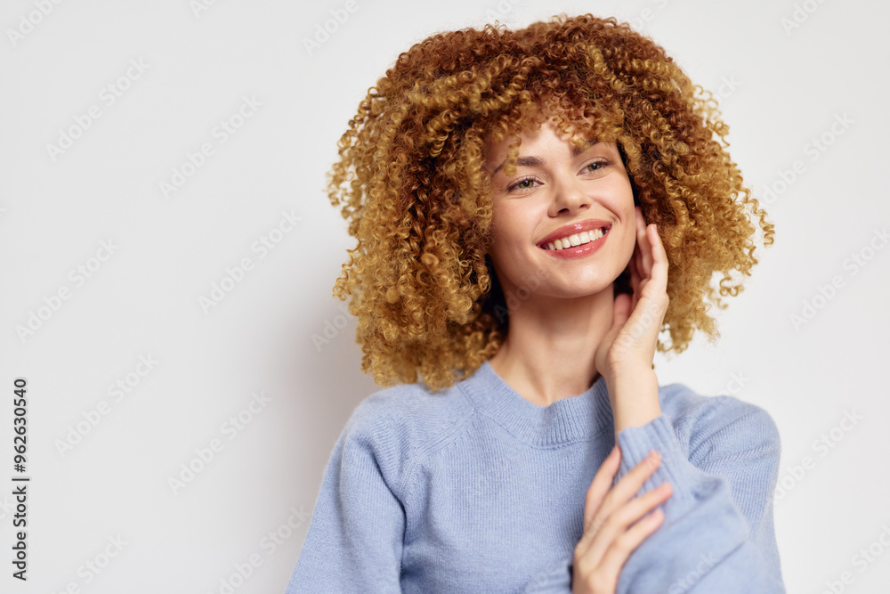 Smiling woman with curly hair in light blue sweater against a neutral background Natural beauty concept showcasing joyful and confident expression for lifestyle imagery Smiling woman with curly hair in light blue sweater against a neutral background Natural beauty concept showcasing joyful and confident expression for lifestyle imagery