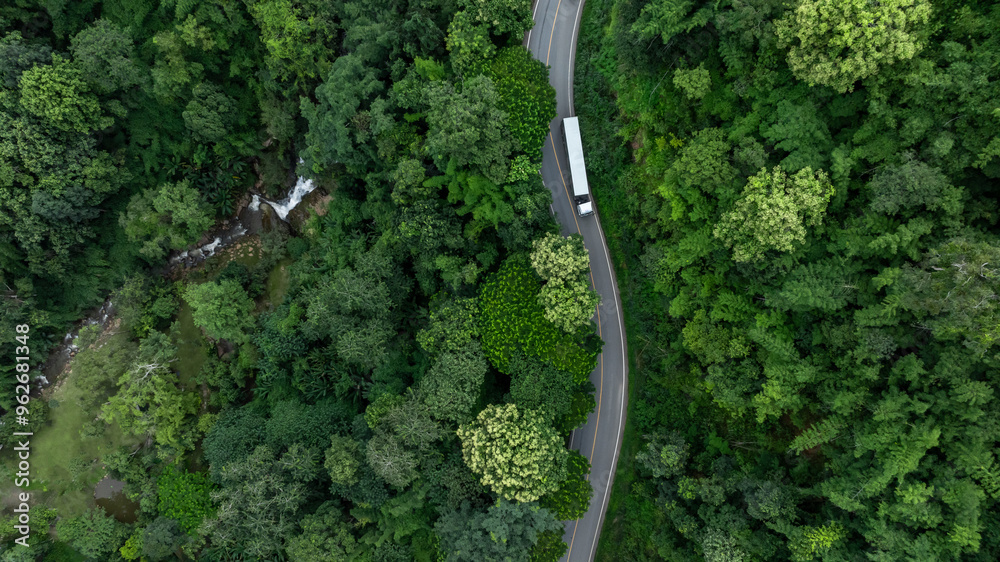 Aerial view semi truck with cargo trailer on road curve with green tree forest, Transportation logistic cargo background, Semi truck trailer on asphalt forest road in green tree forest. Aerial view semi truck with cargo trailer on road curve with green tree forest, Transportation logistic cargo background, Semi truck trailer on asphalt forest road in green tree forest.
