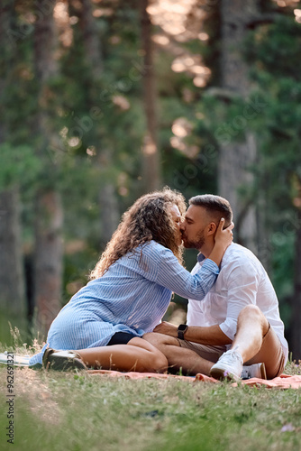 Young couple kissing on picnic in park.