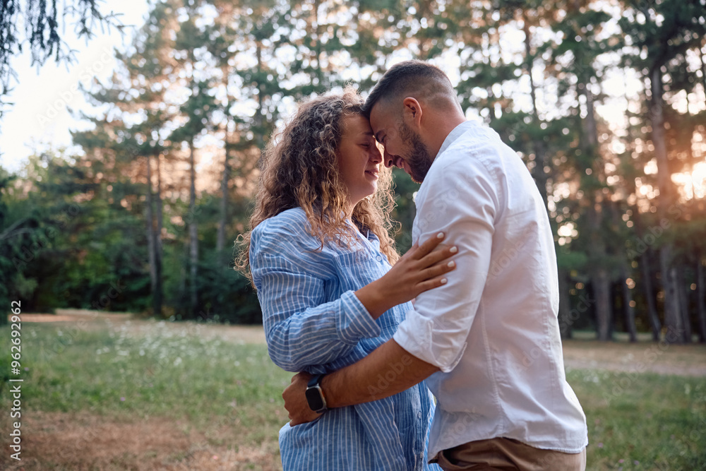 Fototapeta premium Young loving couple standing face to face in nature at sunset.