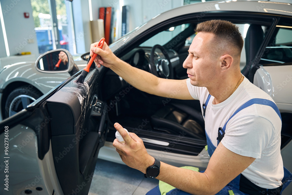 Man in overalls is detailing a car Man in overalls is detailing a car