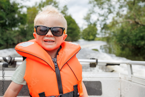 Smiling child in an orange life jacket wearing sunglasses photo