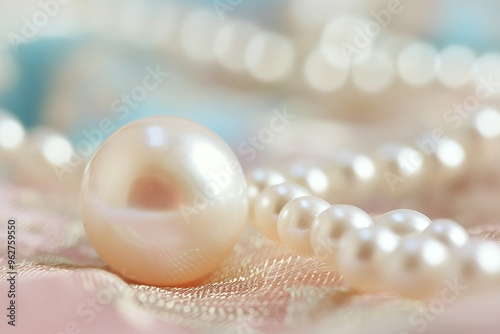 A single pearl lies on a soft, pink fabric with a gold shimmer, surrounded by other pearls.