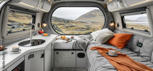 Modern camper van interior with a large window overlooking a mountain landscape. The van has a kitchen and bed, making it perfect for a cozy and comfortable road trip.