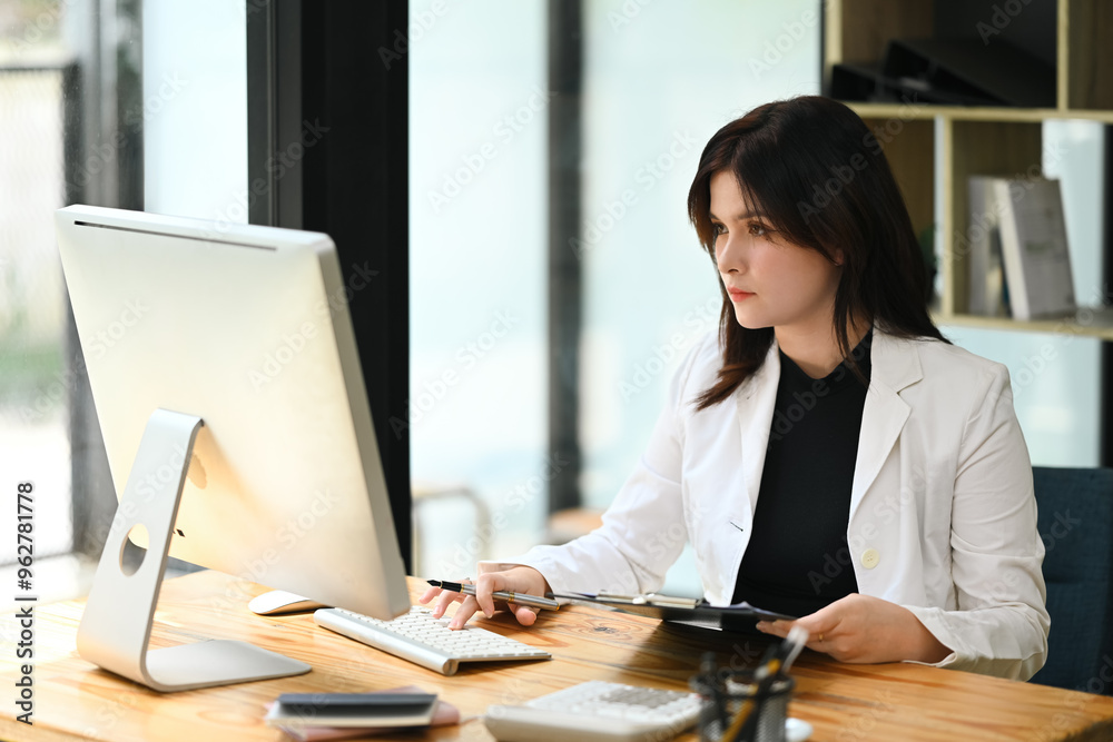 Focused businesswoman looking at computer, working at desk office Focused businesswoman looking at computer, working at desk office