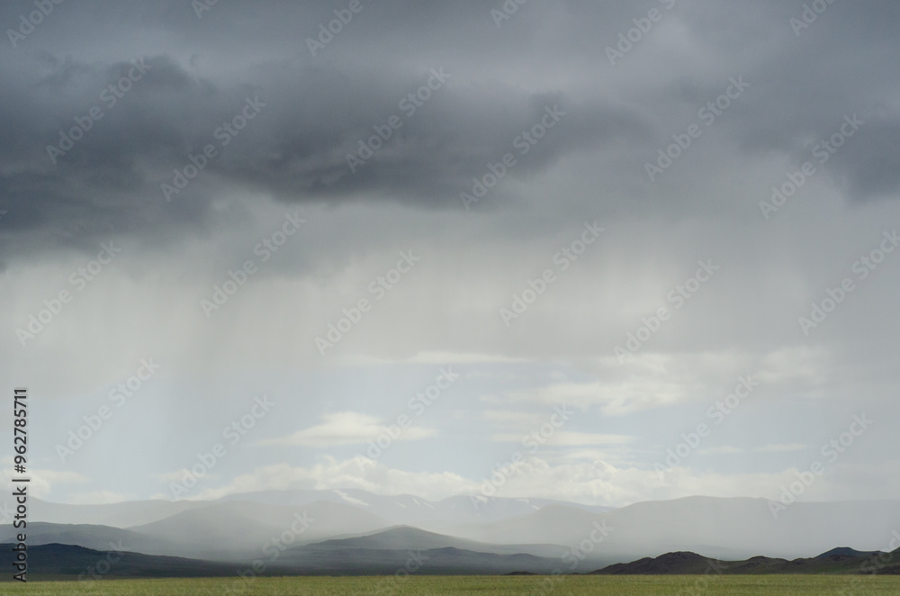 Rays of light shine down from a cloudy sky into a fields. Sun beams ...