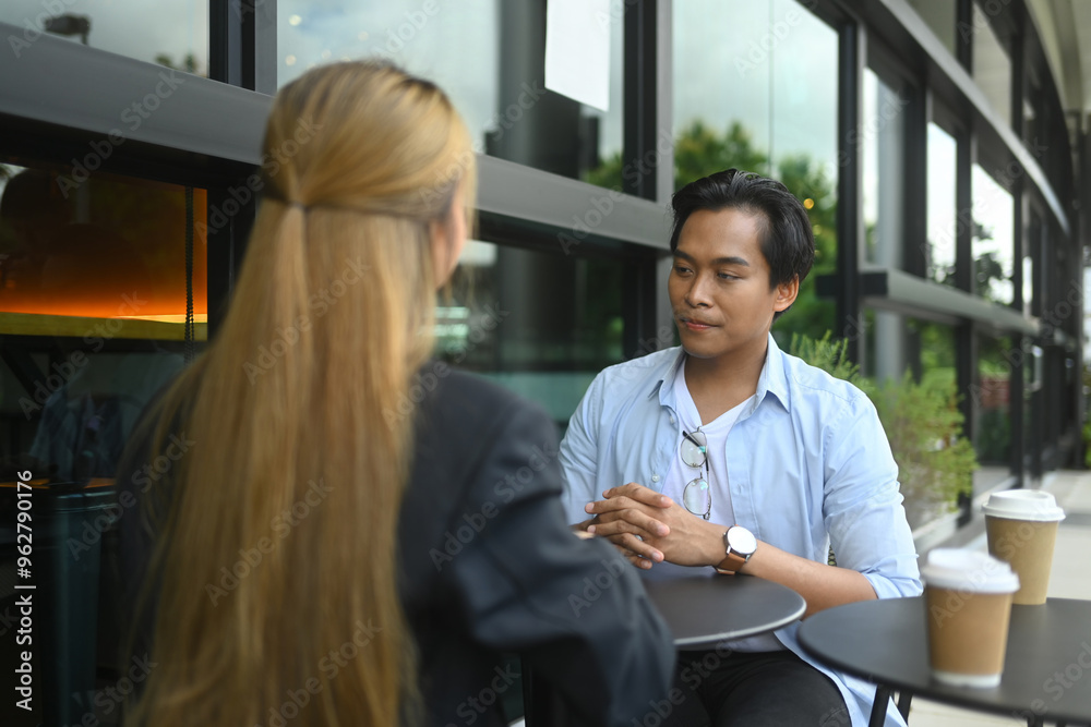 Fototapeta premium Two young businesspeople having a conversation at an outdoor cafe