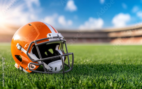 American football and helmet on grass in stadium