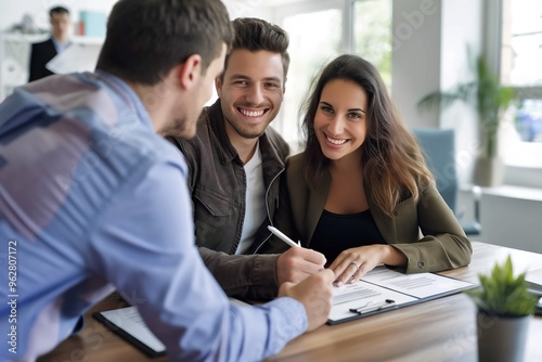 Couple smiling, happy, meeting with real estate agent at bank office. Man and woman signing mortgage loan documents. Banker and client discussing financial investment, credit, and property purchase.