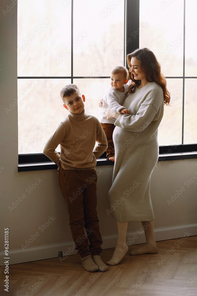 Young mother-to-be with her elder sons are relaxing and playing in the studio together, warm and cozy scene. Happy maternity. Young mother-to-be with her elder sons are relaxing and playing in the studio together, warm and cozy scene. Happy maternity.