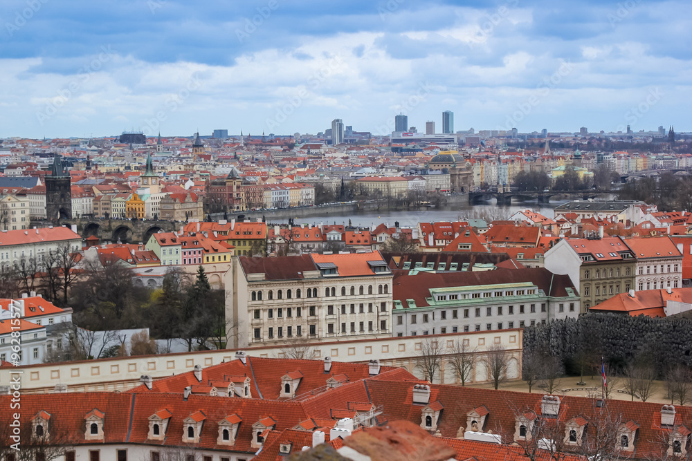 Obraz premium Panoramic view of Prague's historic skyline with red rooftops and modern buildings, perfect for European travel and tourism