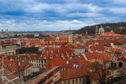 A panoramic view of the historic Prague cityscape with red roofs and architectural landmarks under a cloudy sky, ideal for travel and tourism