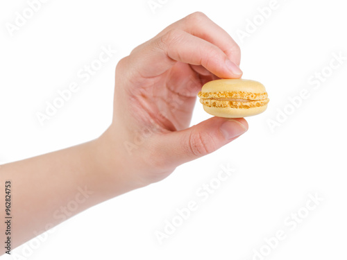 young female hand holding yellow macaron isolated on white