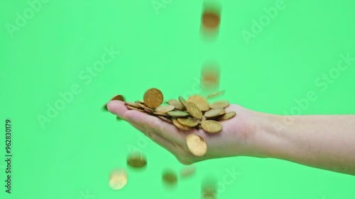 Slow motion video of coins falling into people hand with green background