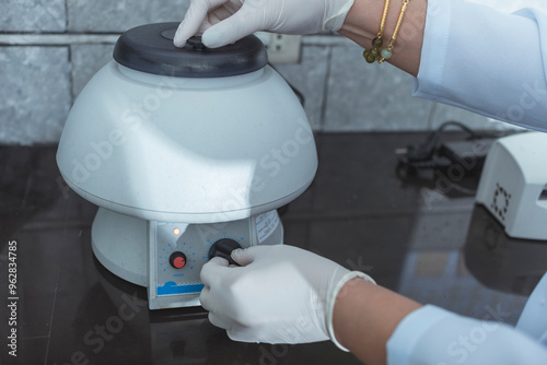 Closeup shot of a laboratory technician operating a tabletop centrifuge.