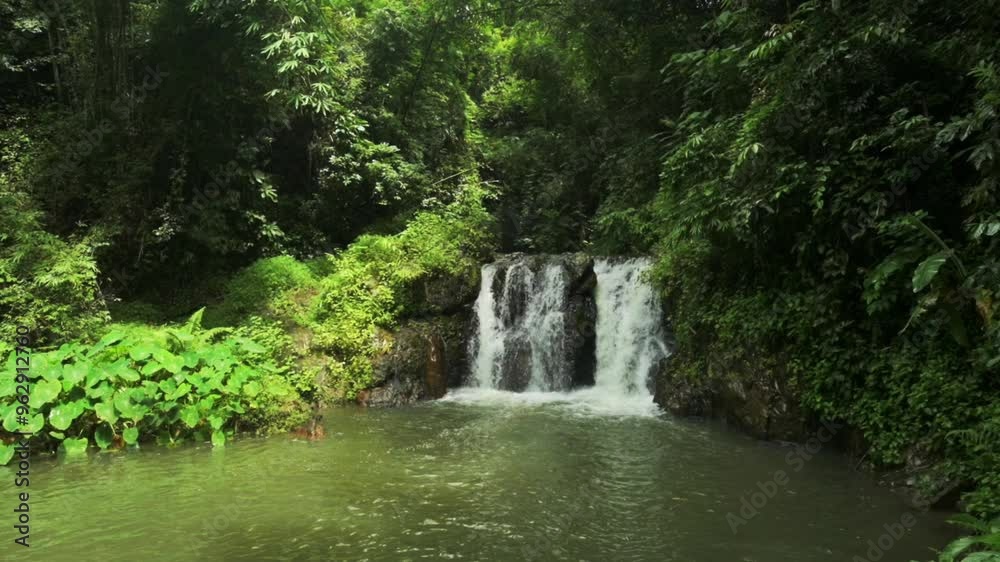 Amazing small waterfall in green tropical rainforest during rainy season. Water stream flowing over the cascade through lush foliage vegetation into the pond in the jungle. Ton Yai Waterfall, Thailand Amazing small waterfall in green tropical rainforest during rainy season. Water stream flowing over the cascade through lush foliage vegetation into the pond in the jungle. Ton Yai Waterfall, Thailand