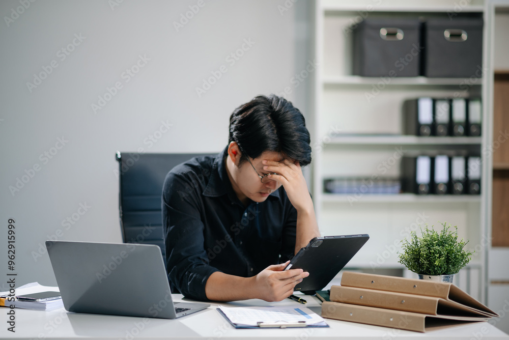 Businessman who is tired and overthinking from working with tablet and laptop Businessman who is tired and overthinking from working with tablet and laptop