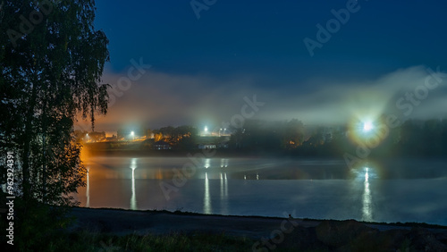 City lights over the river in the fog at night.