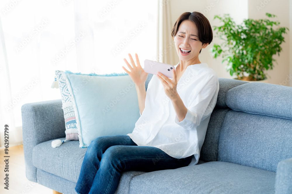 部屋でスマホを操作するミドル女性 部屋でスマホを操作するミドル女性