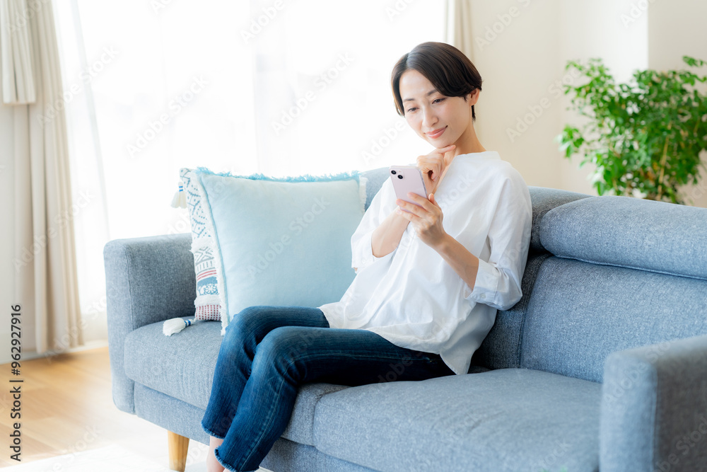 部屋でスマホを操作するミドル女性 部屋でスマホを操作するミドル女性