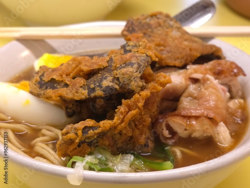 A delicious bowl of ramen served with crispy fried fish, tender slices of meat, soft-boiled eggs with vibrant orange yolks, fresh vegetables, and noodles in a savory broth photo