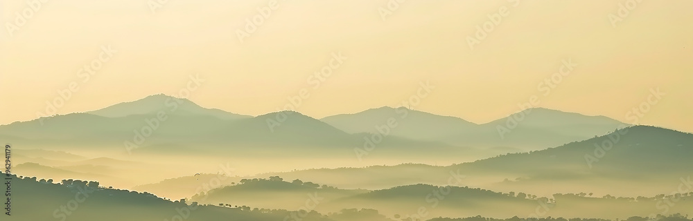 A misty sunrise over a mountain range with a single bird flying in the distance. A misty sunrise over a mountain range with a single bird flying in the distance.