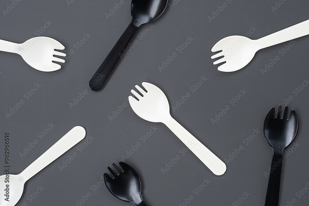 Black and white plastic forks on gray background. Disposable cutlery and minimalism concepts. Black and white plastic forks on gray background. Disposable cutlery and minimalism concepts.