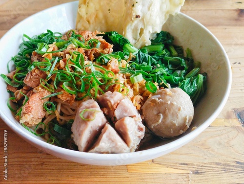 Indonesian Chicken Noodles served with meatballs, mustard greens and a sprinkling of spring onions. Chicken noodles are made from seasoned wheat noodles with pieces of chicken as topping photo