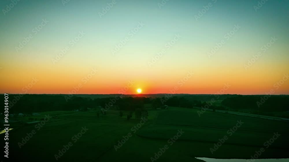 Aerial view of dawn over agricultural fields near the Western Kentucky Parkway, close to Beaver Dam, with the rising sun reflecting off a small pond in the middle of a meadow.