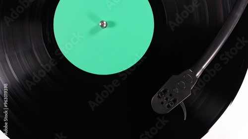 Vinyl retro record on DJ turntable record player. Black vinyl background with green screen in center.