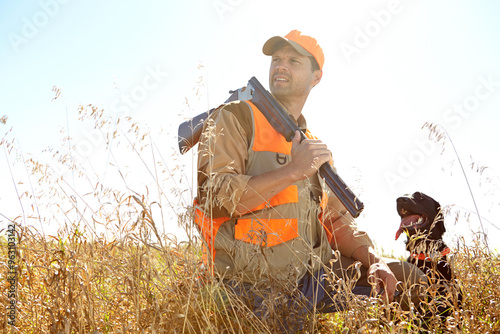 Man, dog and outdoor for hunting gear, shotgun and search for prey together in nature. Mature person, pet animal and hunter support in field to guide in woods, confused and thinking on wildlife