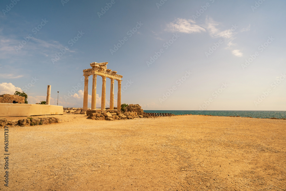The ancient Temple of Apollo ruins in Side, Turkey, standing majestically by the Mediterranean Sea. The image captures the iconic columns of the temple against a backdrop of a clear sky