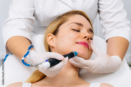 A woman receives a hydrofascial facial treatment in a modern clinic, focusing on advanced skin rejuvenation techniques and contemporary skincare practices.