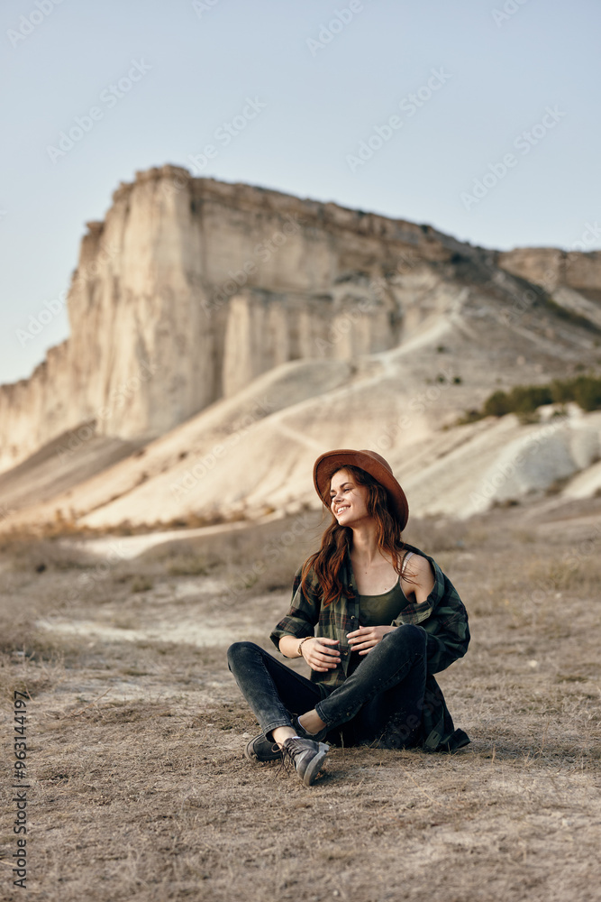 Woman in hat sitting in front of majestic desert mountain background Woman in hat sitting in front of majestic desert mountain background