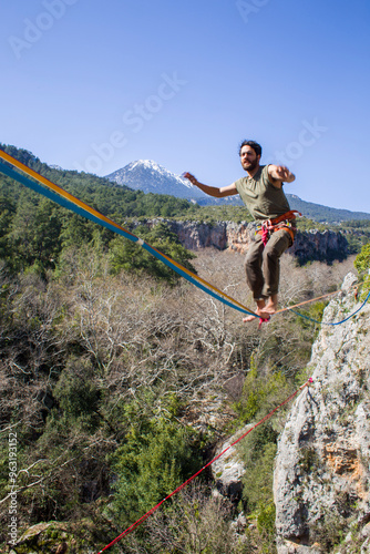 A tightrope walker walks along a cable stretched over a canyon.