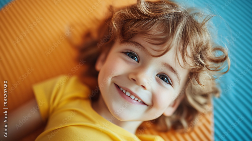 Portrait of happy young boy with beautiful blue eyes and curly blonde hair smiling while lying down Portrait of happy young boy with beautiful blue eyes and curly blonde hair smiling while lying down
