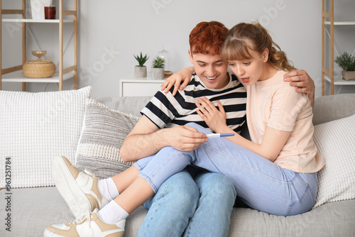 Happy young couple with pregnancy test at home