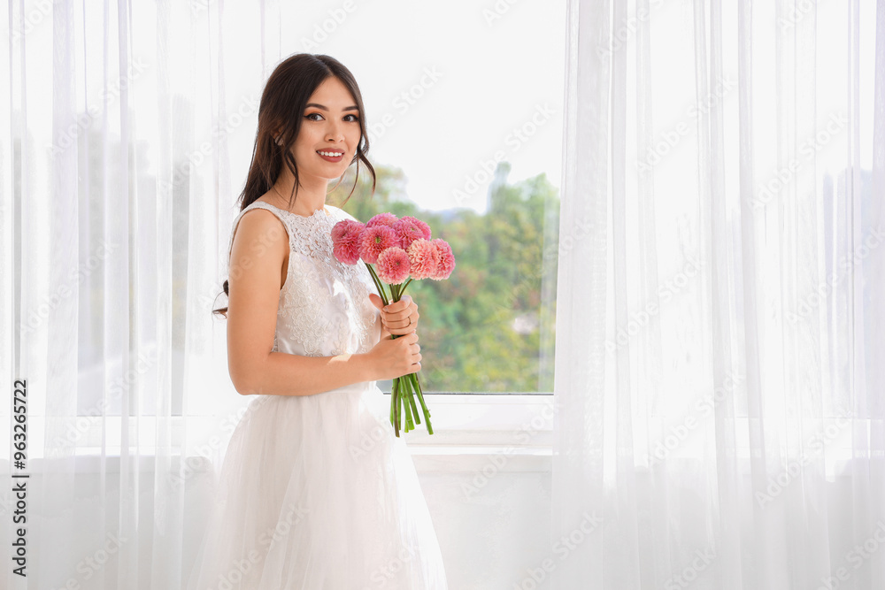 Beautiful young Asian bride with wedding bouquet of pink dahlias near window at home Beautiful young Asian bride with wedding bouquet of pink dahlias near window at home